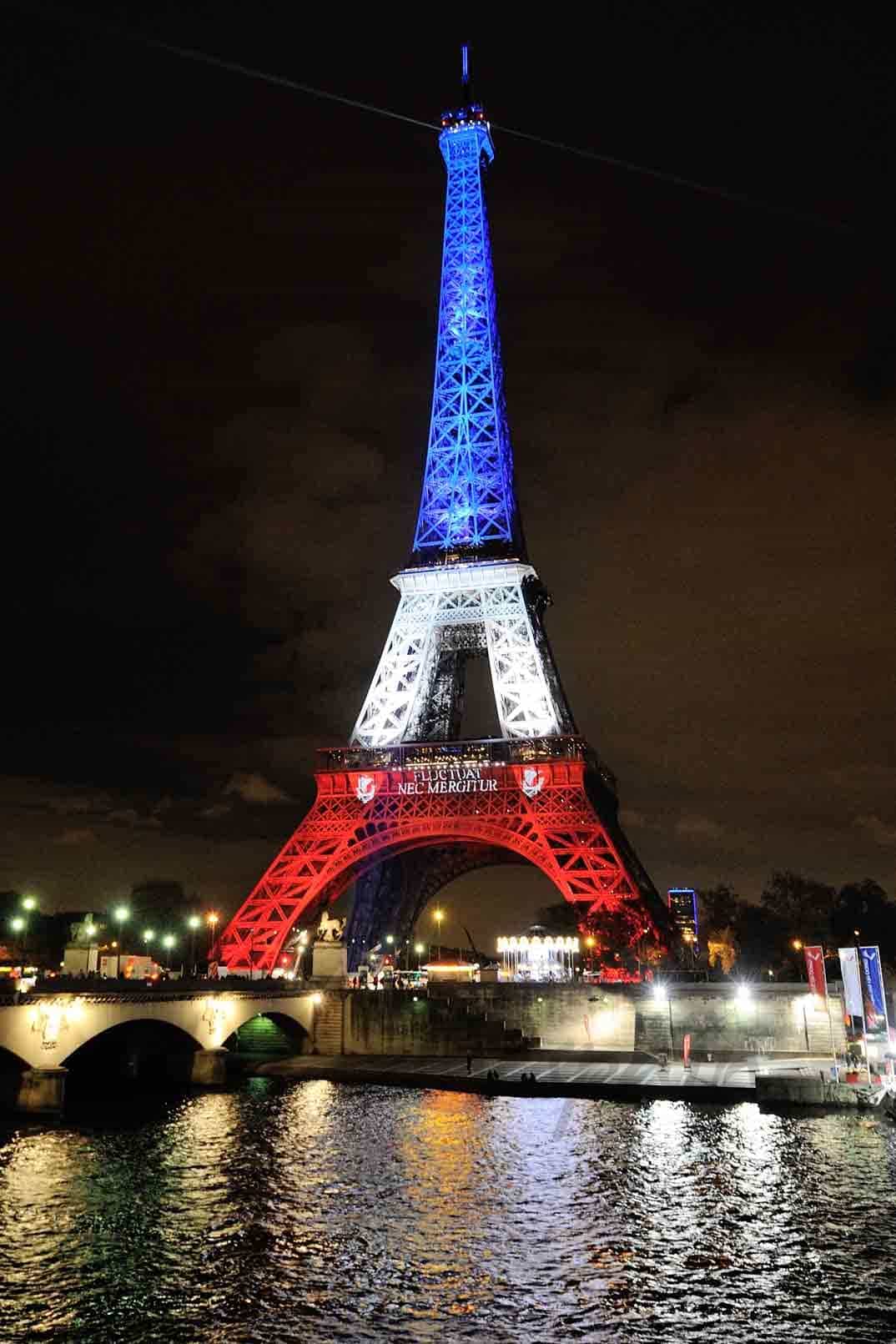 torre eiffel iluminada con los colores de la bandera francesa