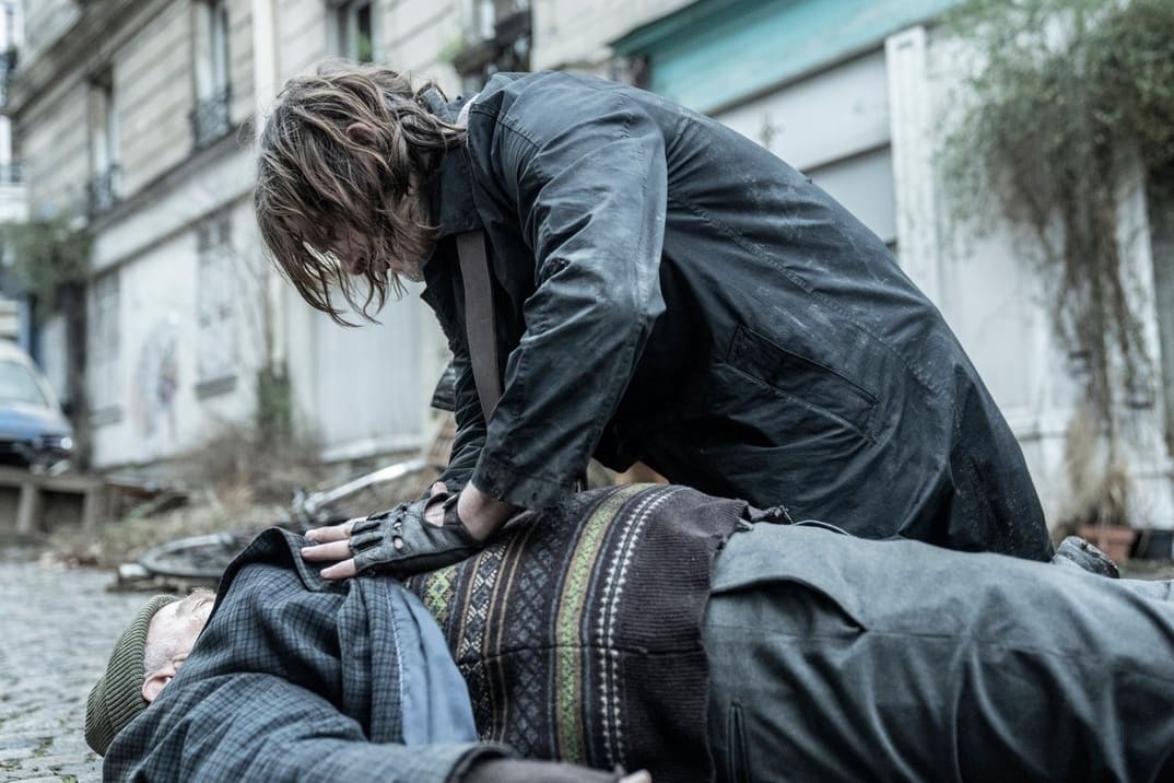 Imagen promocional de "Daryl Dixon" 1x05 - Daryl inclinado sobre Antoine que está tirado en el suelo gravemente herido